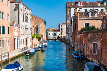 Vue d'un canal à Venise dans le Cannaregio depuis un pont avec des bateaux accostés et des...