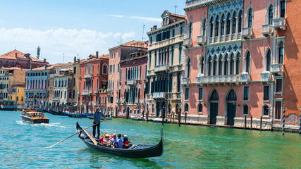 Gondole et son gondolier avec des touristes à Venise sur le grand canal et avec des vieux bâtiments colorés par une journée ensoleillée