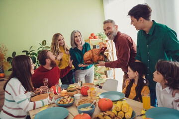 Photo of happy family spouses serving table main holiday dish stuffed turkey celebrating thanksgiving day indoors