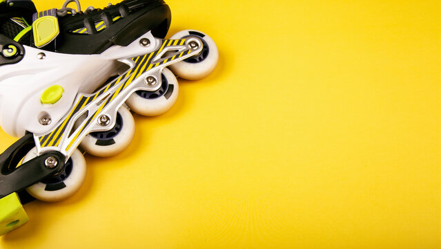 Stylish roller skates on yellow background, top view. Inline skates isolated on yellow, extreme sports background