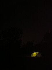 Illuminated tent under the night starry sky