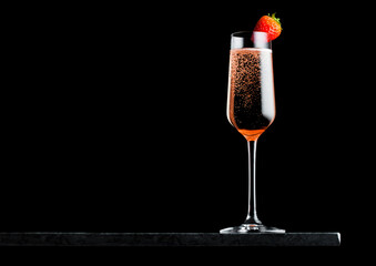 Elegant glass of pink rose champagne with strawberry on top on black marble board on black background. Space for text