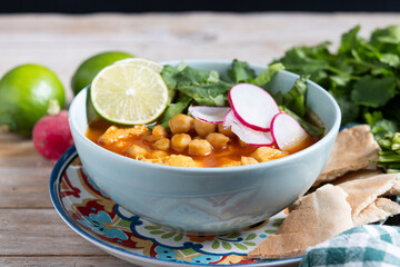 Traditional mexican red pozole soup on wooden table