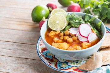 Traditional mexican red pozole soup on wooden table. Copy space