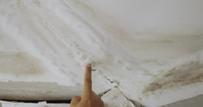 Male finger is peeling paint on ceiling, Office building or house problem for house service. High definition shot at 4K, 50 fps video footage.