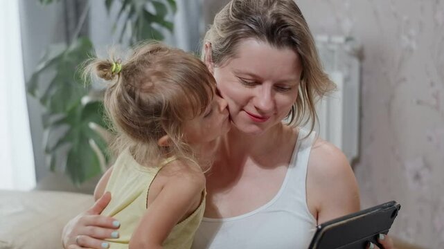 Happy mother with daughter choosing what to buy for daddy on Father's Day on the online platform. 
