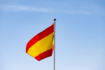 Spanish national flag waving against a clear blue sky, symbolizing patriotism and national identity