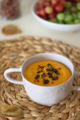 Pumpkin and potato creamy soup, bowl of grapes, jars of nuts and autumn leaves on the table. Selective focus.