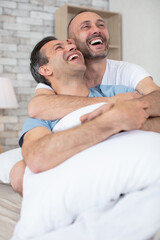 Fototapeta premium gay couple hugging and smiling in bed