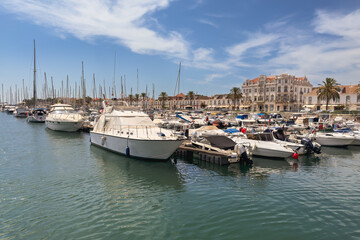 Fototapeta premium Boats docked in a marina with a historic town and palm trees in the background.