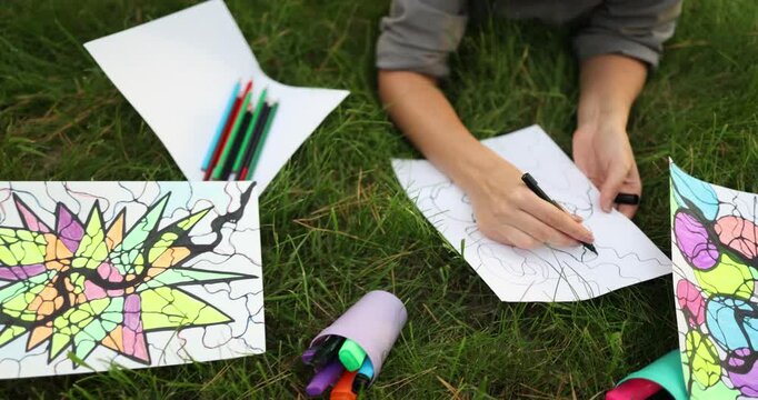 An individual enjoys coloring in nature, showcasing their creativity and finding joy and relaxation through art