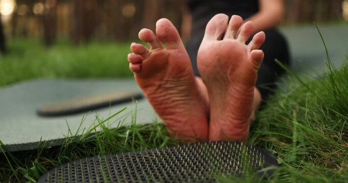 A relaxing outdoor yoga session with bare feet lying on a mat after standing on nails surrounded by the beauty of nature