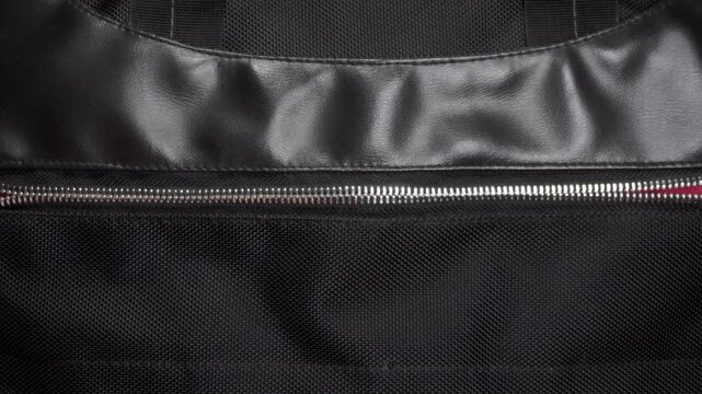 Hand opens and closes the metal zipper. A close-up of the black bag pocket