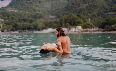 Fototapeta premium couple in love in water swim in the sea in the evening and love each other, long-haired couple.