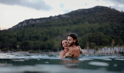Fototapeta premium couple in love in water swim in the sea in the evening and love each other, long-haired couple.