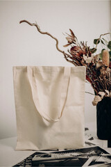 Shopping bag mockup on a white table with a flowerpot with flowers