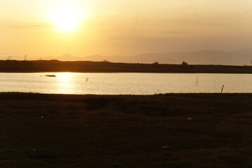 Vibrant hues of gold and crimson fill the sky as the sun sets. Fluffy clouds drift across, catching the last light, creating a breathtaking tapestry that transforms the horizon into a masterpiece of c