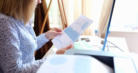 A woman in the office looks at a financial report on paper, close-up. The workflow of a financier