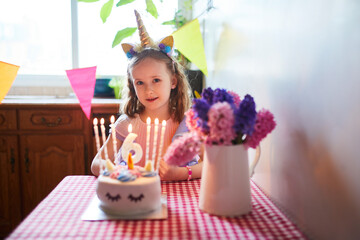 Happy little girl celebrating her sixth birthday and making a wish. Little kid with birthday cake and candle