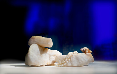 Template, white marble podium, stones and seashell, jewelry pearls. Empty space. Deep blue, cobalt blue background. Background for design. Space for presentation product. Pedestal cosmetics fashion