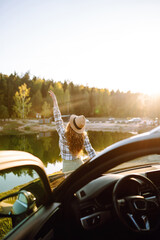 A woman in a plaid shirt enjoys a peaceful sunset by the lake, celebrating nature while standing...