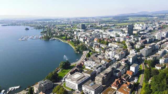 Cinematic panoramic view of the city of Zug on the shores of Lake Zugersee in Switzerland featuring the central train station