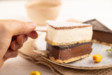 Chocolate and Vanilla Cake pops Marshmallow with hand with cup of coffee on white wooden, side view, selective focus.