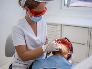 A dental professional performs a routine examination on a patient in a bright clinic. The patient...