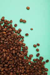 Roasted coffee beans on mint background. Space for text