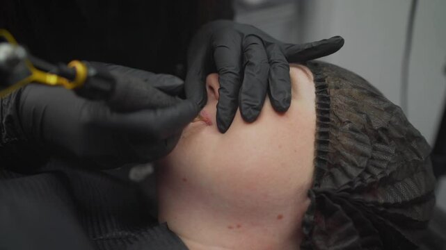 Beautician performing permanent makeup treatment on woman's face.
