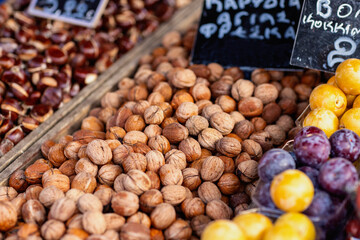 A vibrant display of assorted nuts and dried fruits fills the market stall with earthy tones, enticing visitors to sample the seasonal harvest as autumn unfolds.