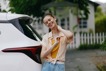 Young woman leaning against a car, smiling joyfully, wearing a casual outfit The scene conveys happiness and relaxation in a bright, sunny environment