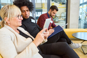 Diverse team collaborating on project with tablet and documents in modern office