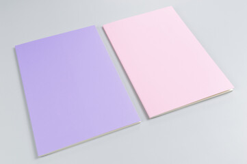 Top view of pink and purple notebooks on grey background. School, office wallpaper. Flat lay, copy space.