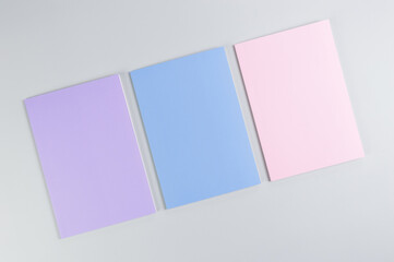 Top view of pink, purple and blue notebooks on grey background. School, office wallpaper. Flat lay, copy space.