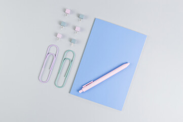 Top view of blue notebook on grey background. Paperclips, pen and pins. School, office wallpaper. Flat lay, copy space.