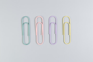 Top view of colorful paperclips on grey background. School, office wallpaper. Flat lay, copy space.
