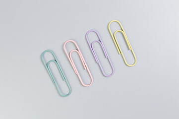 Top view of colorful paperclips on grey background. School, office wallpaper. Flat lay, copy space.