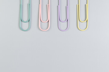 Top view of colorful paperclips on grey background. School, office wallpaper. Flat lay, copy space.