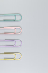 Top view of colorful paperclips on grey background. School, office wallpaper. Flat lay, copy space.