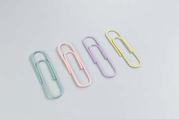 Top view of colorful paperclips on grey background. School, office wallpaper. Flat lay, copy space.