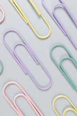 Top view of colorful paperclips on grey background. School, office wallpaper. Flat lay, copy space.