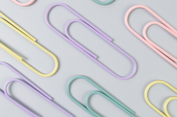 Top view of colorful paperclips on grey background. School, office wallpaper. Flat lay, copy space.