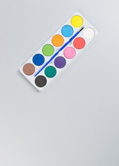 Top view of watercolor and paint brush on grey background. Painting, art, copy space, flat lay.