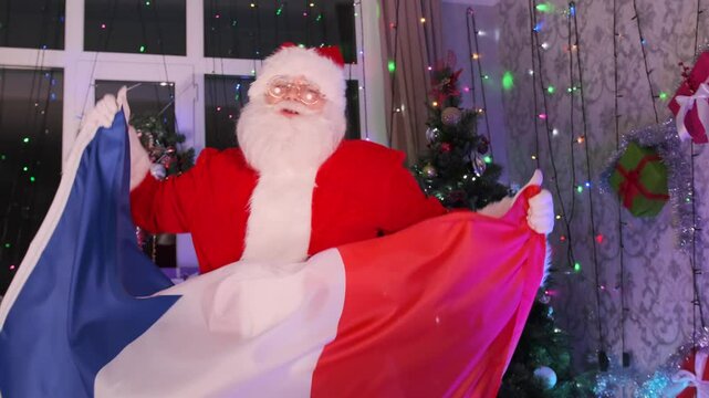 Santa Claus dancing with French flag in his hands against backdrop of holiday decorations Christmas party and Happy New Year. Mid shot. Xmas in France.