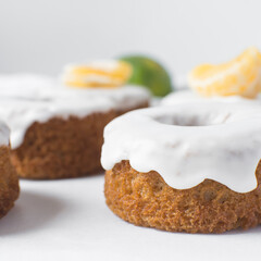 Iced mini bundt cake on a white tray, vanilla bundlette cakeswith a clementine segment on a white background, small vanilla bundt cakes with an icing glaze