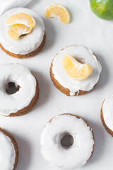 Iced mini bundt cake on a white tray, vanilla bundlette cakeswith a clementine segment on a white background, small vanilla bundt cakes with an icing glaze