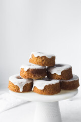 Iced mini bundt cakes on a white plate, vanilla bundlette with a clementine segment on a plate, small vanilla bundt cakes with an icing glaze