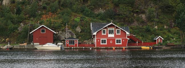 Red boat sheds and cottages at the shore of the Tengs River, Egersund, Norway.