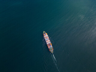 A container ship sails across the calm blue waters